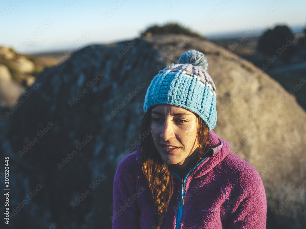 Portrait of attrtactive female climber wearing a hat at sunset in a rocky scenery Portrait of attrtactive female climber wearing a hat at sunset in a rocky scenery