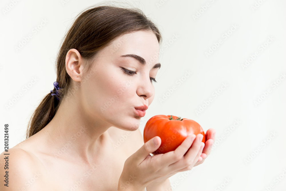 Beautiful girl is showing and kiss a big red tomato healthy high nutrition vegetable good for skin Beautiful girl is showing and kiss a big red tomato healthy high nutrition vegetable good for skin