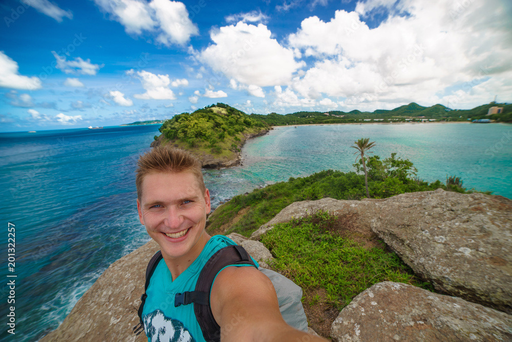 Handsome tourist takes travel selfie at the island