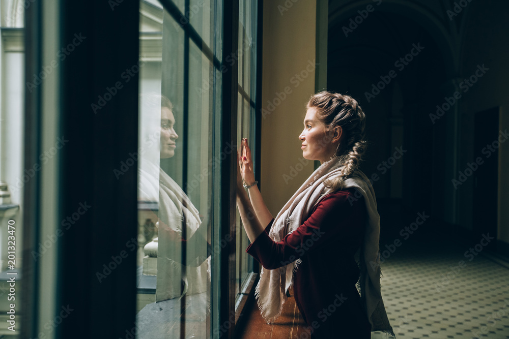 Dark profile portrait of thoughtful blond woman near big window. Melancoly mood concept. Dark profile portrait of thoughtful blond woman near big window. Melancoly mood concept.