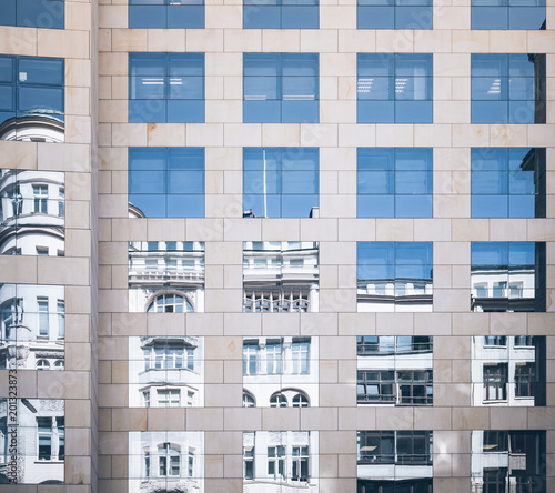 historic building mirrored in glass facade of modern office building old and new contrasting concept