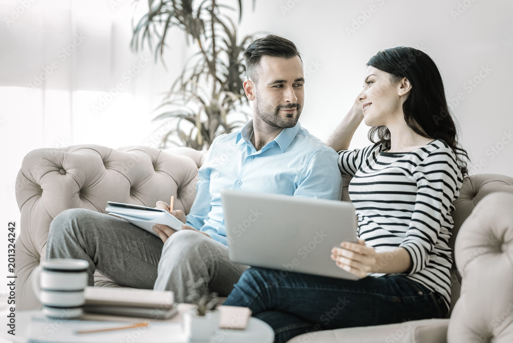 Love during work. Pleasant gay two colleagues looking at each other while working and posing on sofa Love during work. Pleasant gay two colleagues looking at each other while working and posing on sofa