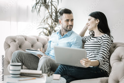 Love during work. Pleasant gay two colleagues looking at each other while working and posing on sofa