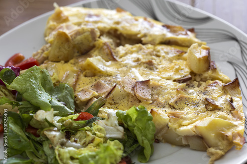 Fresh omelette with ham and potatoes on plate