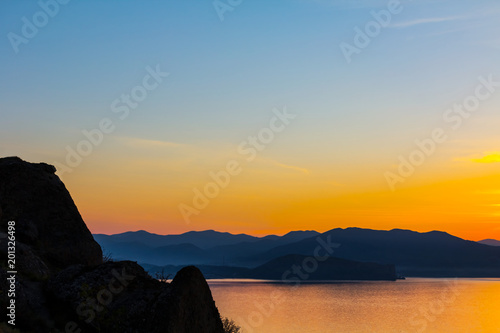 quiet sea bay at the dusk with rocky coast silhouette