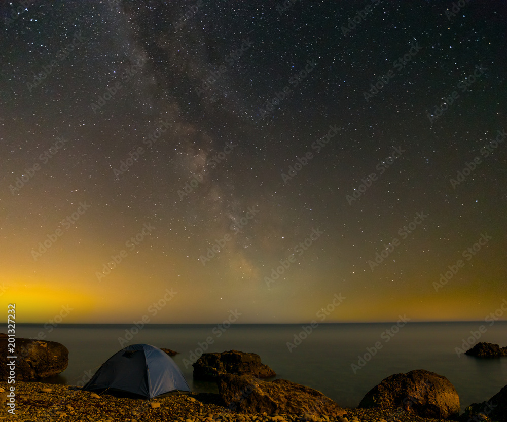 touristic tent on a sea coast at the night under a milky way