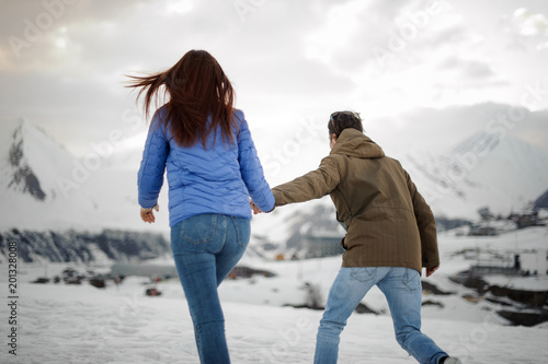 guy leads a girl for a walk towards the snow mountains