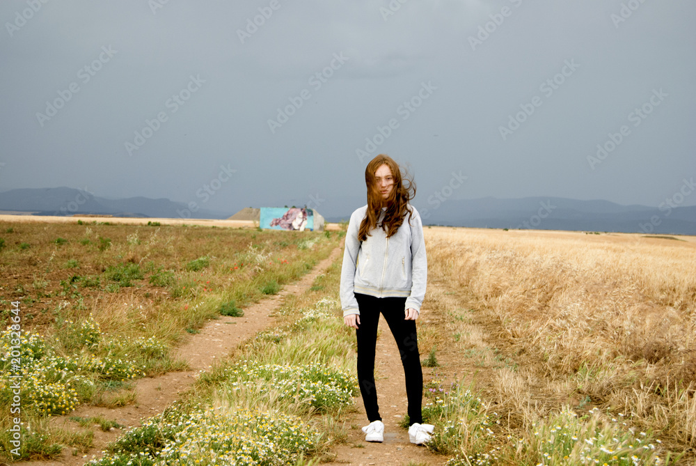 Chica joven posando en un camino solitario al atardecer
