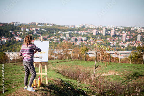 Artistic girl paint on canvas on easel outdoor
