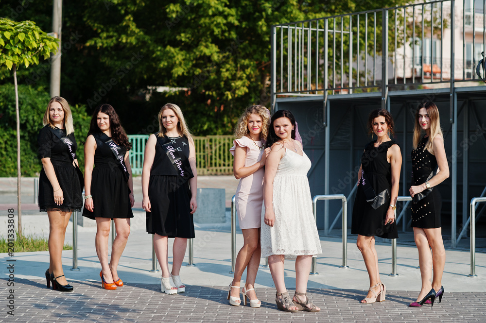 Obraz premium Group of 7 girls wear on black and 2 brides at hen party.