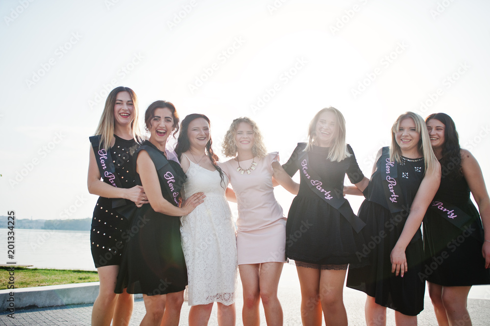 Fototapeta premium Group of 7 girls wear on black and 2 brides at hen party.