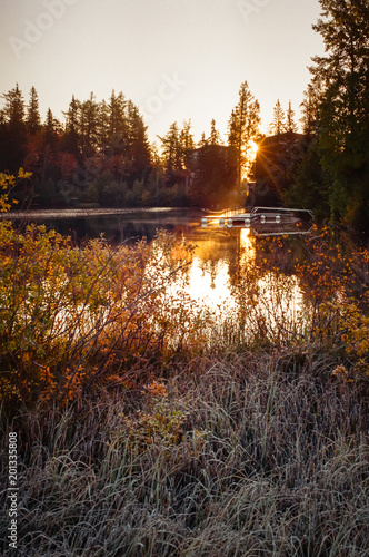 Marvelous panorama of wild nature, mountain lake and warm rays of descending sun pouring all around. Shot with film camera with grain.