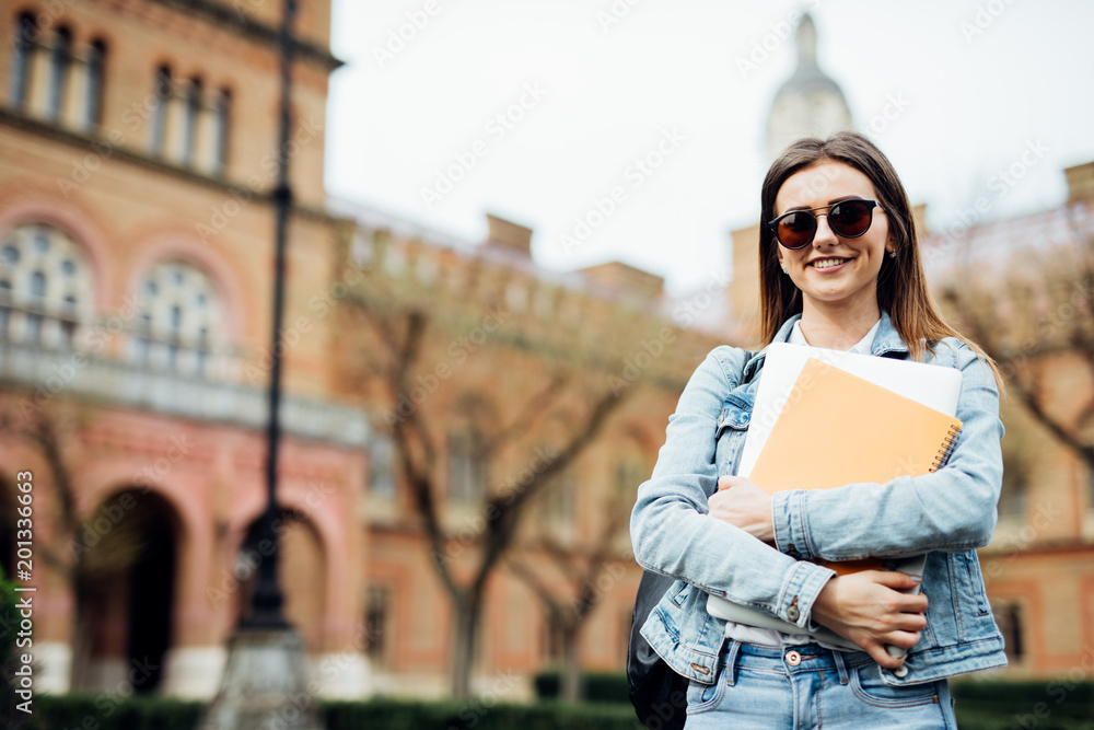 smartyoung woman college student on campus with notebooks in hands