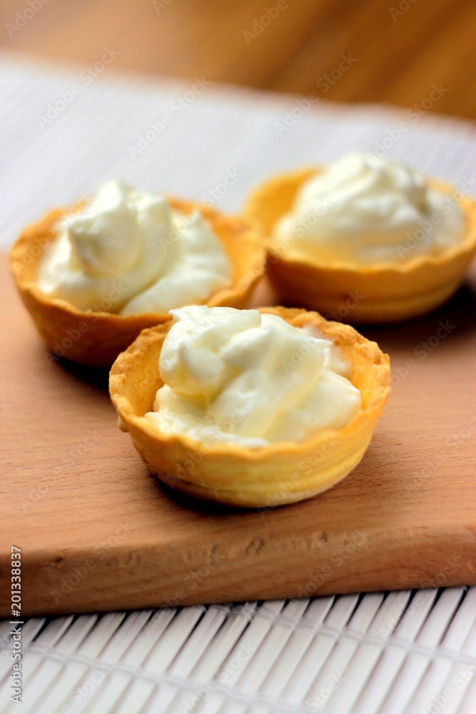 three cakes with cheese cream on a wooden background