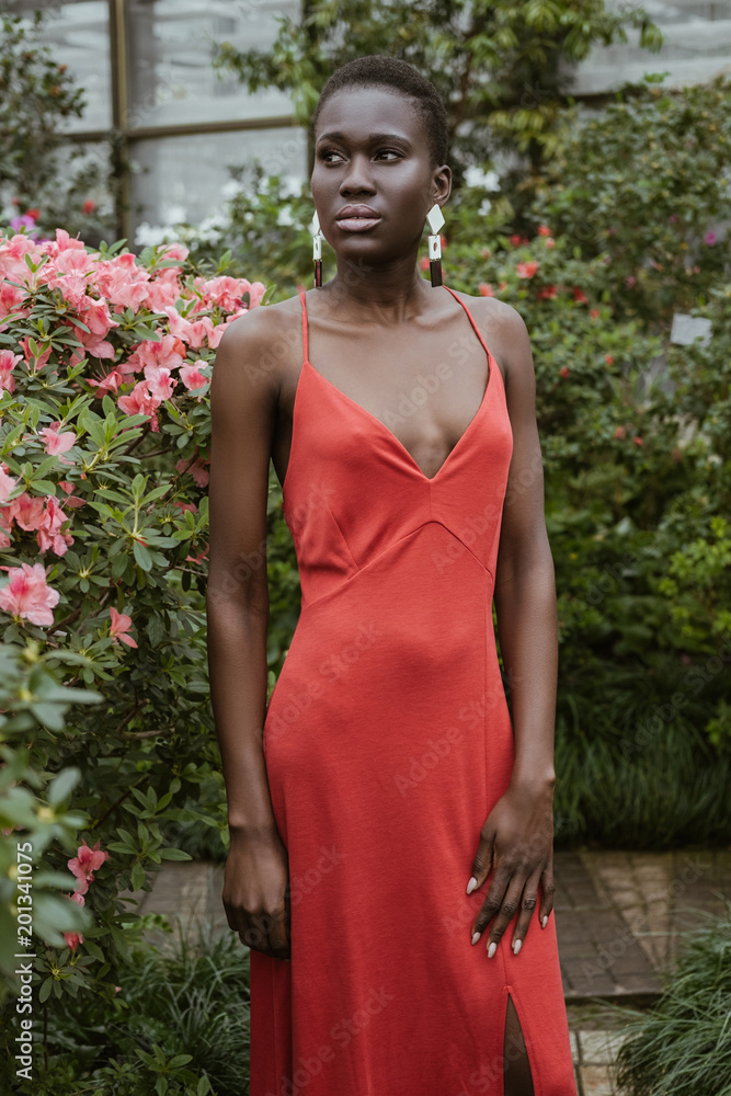 attractive african american girl with short hair in red dress posing in  garden with flowers Stock Photo | Adobe Stock