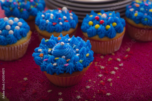 Colorful cupcakes with different Tastes. Small beautiful cakes on red table top. Close up