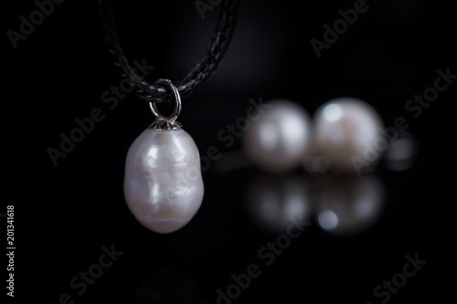 jewelry concept natural pearl pendant on the background of pearl earrings in the defocus