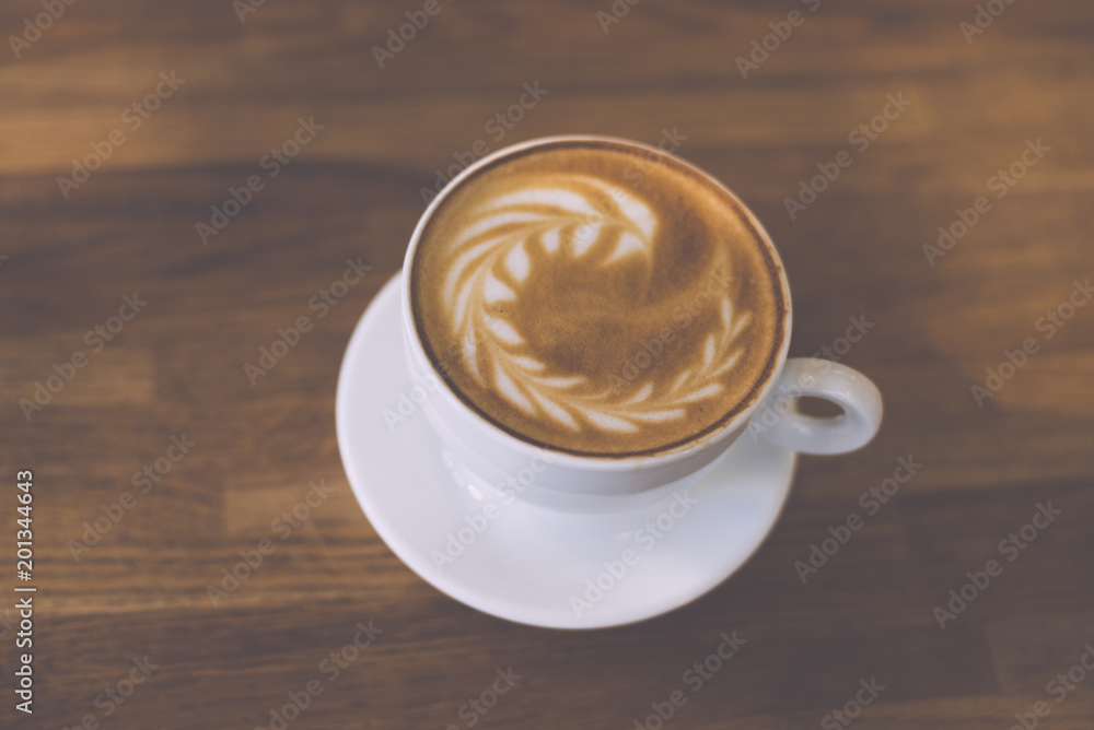 A Cup of hot latte art coffee on wooden table A Cup of hot latte art coffee on wooden table
