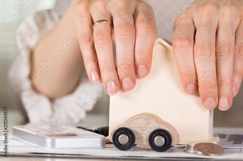 Female hands grasp small wooden house.