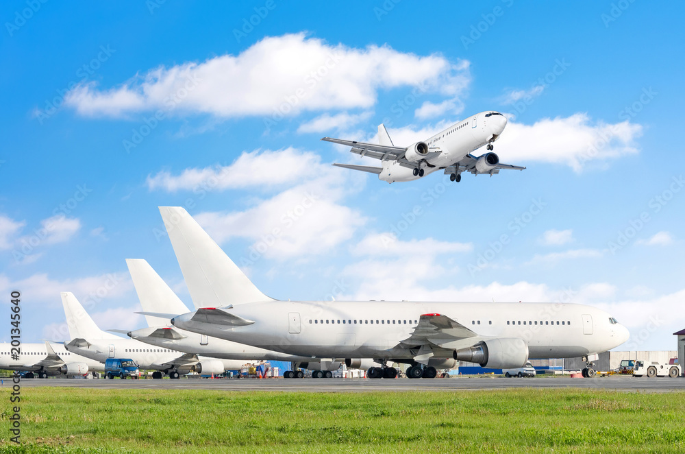 Row of passenger aircraft, airplane parked on service before departure. at the airport, other plane push back tow. One landing on the runway in the sky. Row of passenger aircraft, airplane parked on service before departure. at the airport, other plane push back tow. One landing on the runway in the sky.