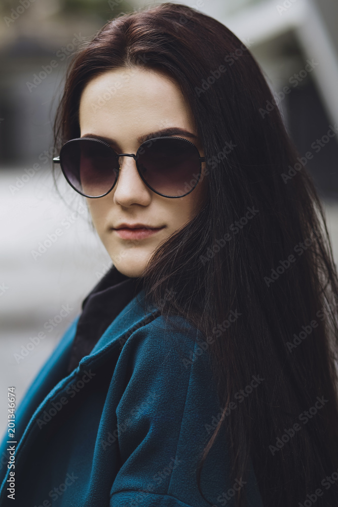Beautiful brunette girl. Fashionable, stylish with black hair, in a coat and jeans