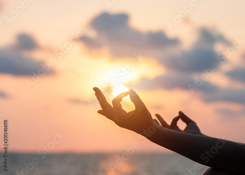 Mantra yoga meditation practice with silhouette of woman in lotus pose having peaceful mind relaxation on the beach outdoor training with sunset golden hour heavenly sky 