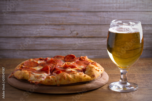 Beer and pepperoni pizza on wooden table. Glass of beer. Ale and food concept. horizontal