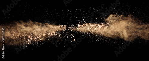 Abstract colored brown powder explosion isolated on black background.