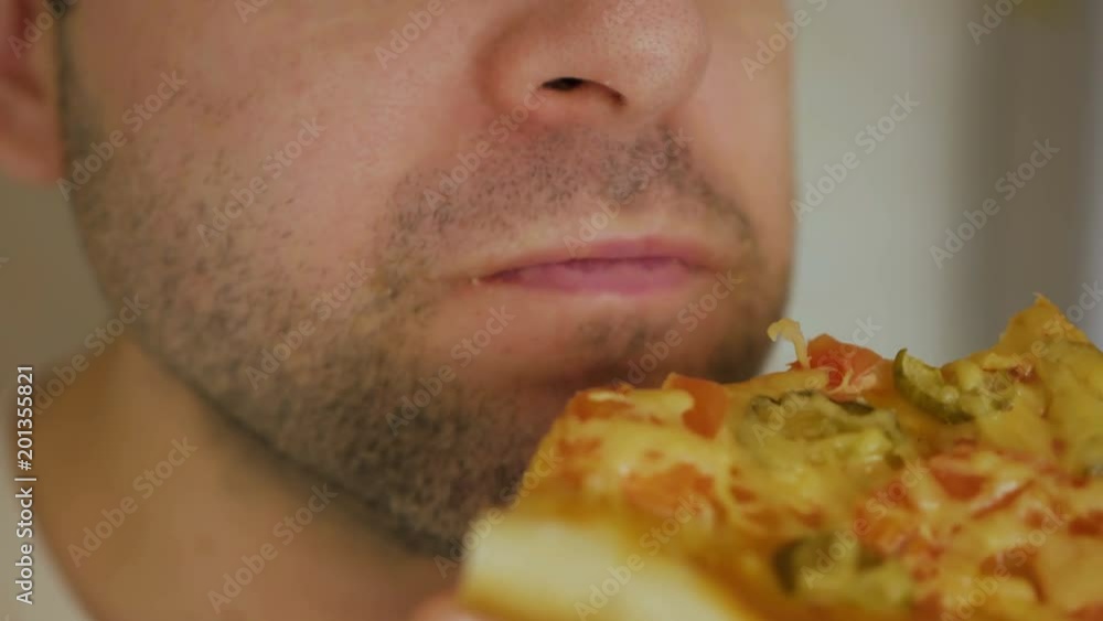 Caucasian man eating pizza. Hungry male taking a bite from pizza. Closeup. Caucasian man eating pizza. Hungry male taking a bite from pizza. Closeup.