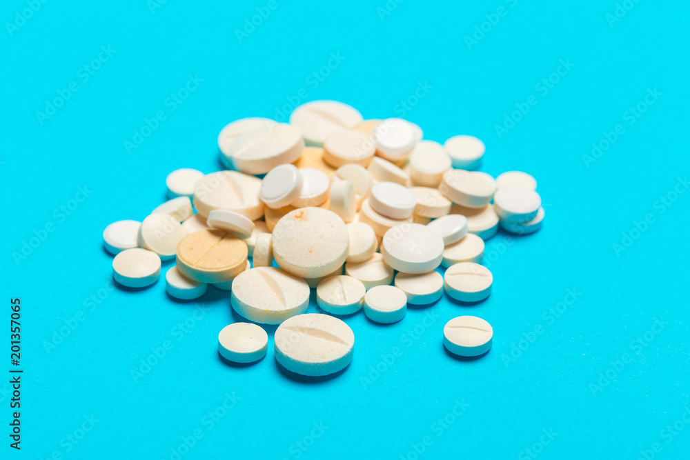 Pills are scattered over a blue background Pills are scattered over a blue background