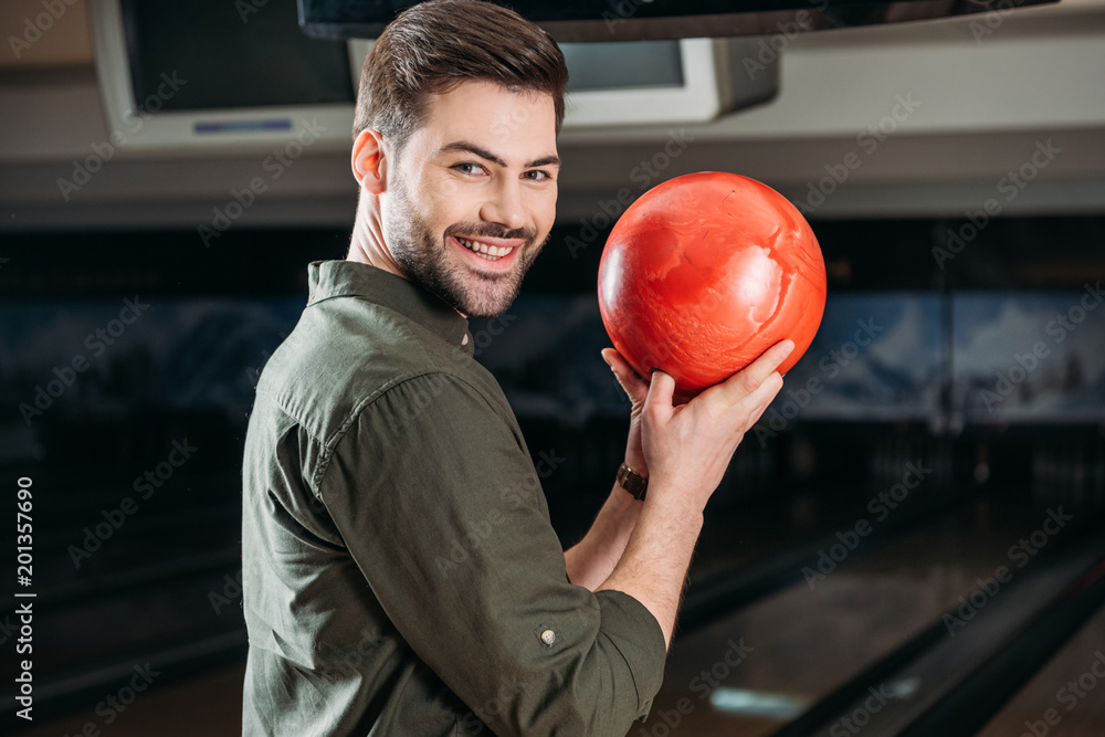 smiling young man holding bowling ball and looking at camera Stock Photo |  Adobe Stock