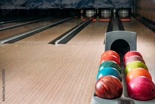 stand with colorful bowling balls in club in front of alleys