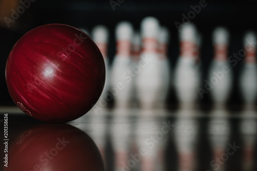 close-up shot of red bowling ball on alley in front of pins