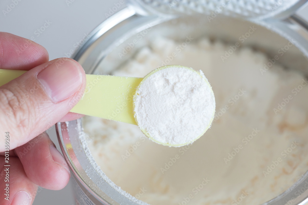hand holding milk powder in measuring spoon for baby. hand holding milk powder in measuring spoon for baby.