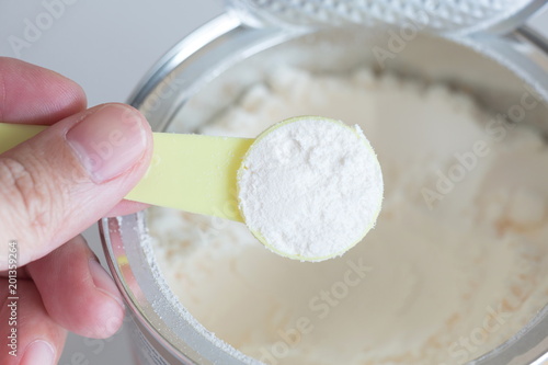 hand holding milk powder in measuring spoon for baby.
