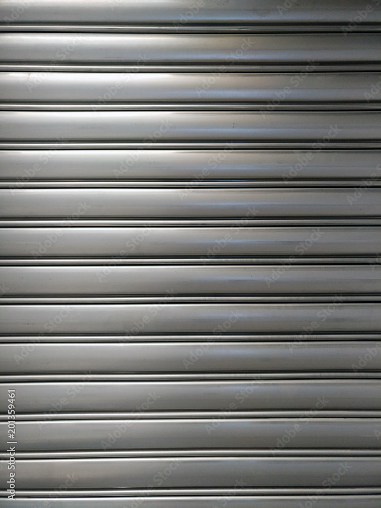 Obraz premium pattern of roll-up door in horizontal lines, shiny metallic material, with glowing part and shady part