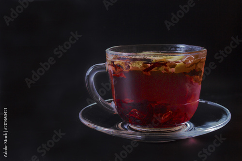 one aromatic glass mug of fruit tea on a black background