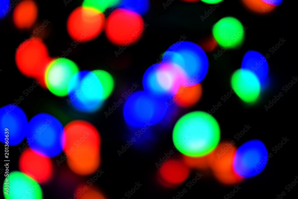 Colorful abstract bokeh out of focus background of christmas lights on black.