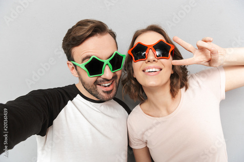 Amazing couple friends make peace gesture wearing sunglasses.