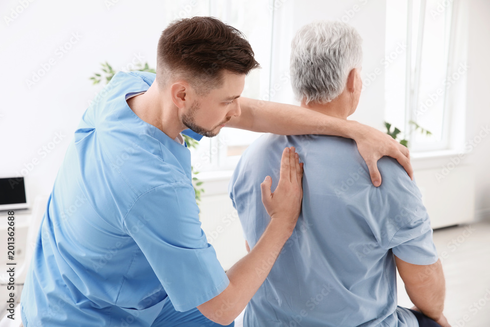 Fototapeta premium Young physiotherapist working with senior patient in clinic