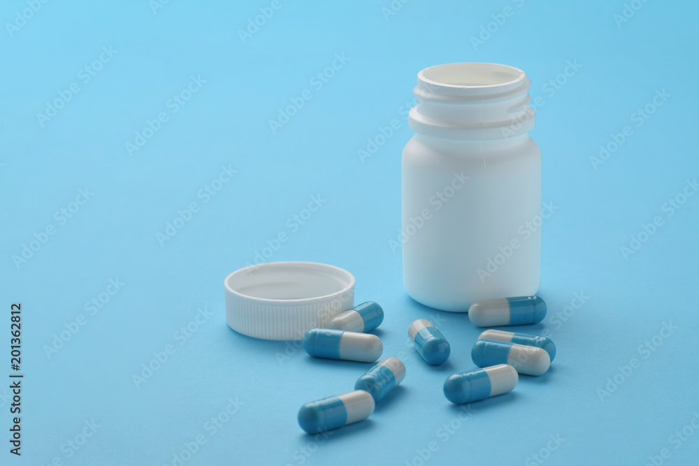 Container and capsules on blue background. Isolated Container and capsules on blue background. Isolated