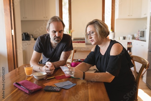 Couple calculating invoice bills in kitchen photo