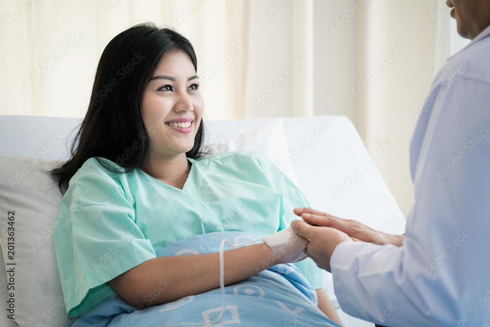 Hand of man doctor reassuring his female patient in bed at hospital. Medical ethics and trust concept.. Hand of man doctor reassuring his female patient in bed at hospital. Medical ethics and trust concept..