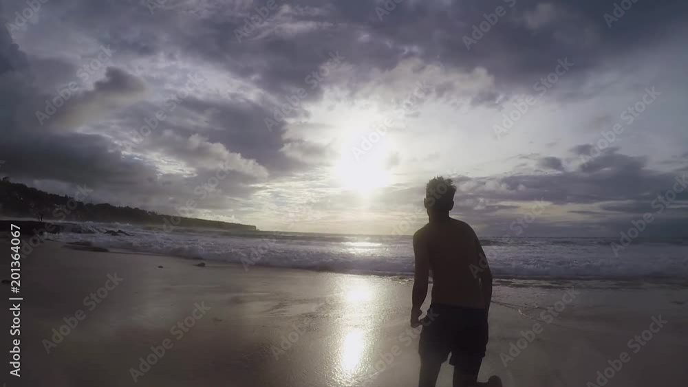 Silhouette of a man running into the ocean at sunset in slow motion Silhouette of a man running into the ocean at sunset in slow motion