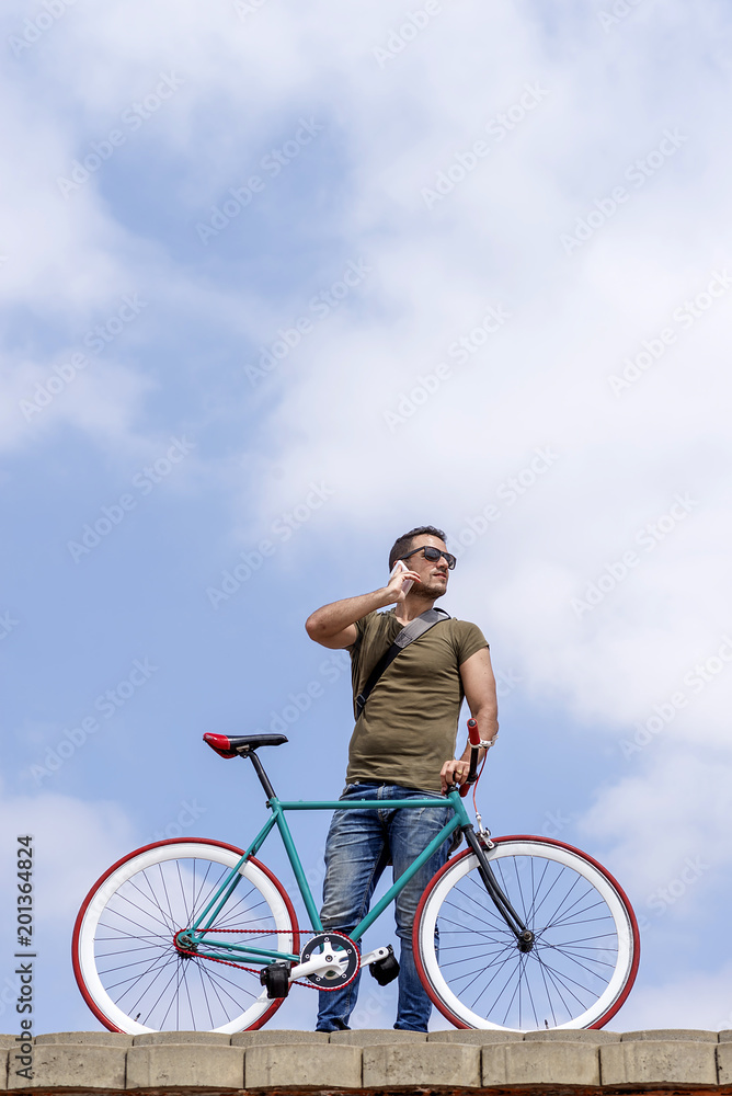 Attractive young man standing outdoors and calling on the phone Attractive young man standing outdoors and calling on the phone