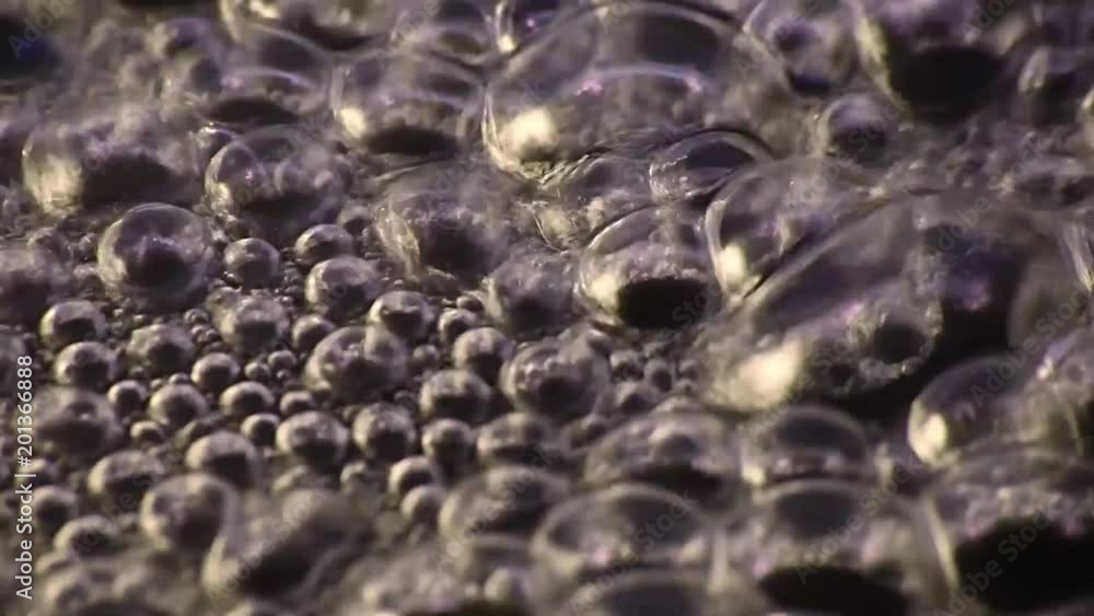 Bubbles of water boiling and evaporating in a black pan. Close up Bubbles of water boiling and evaporating in a black pan. Close up