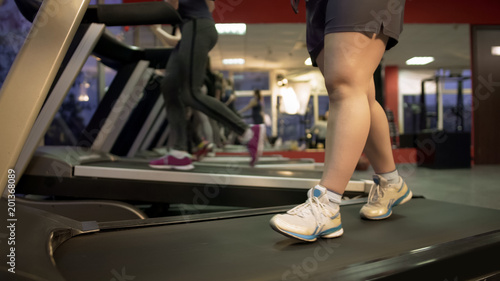Feet of fat woman walking slowly on treadmill, healthy life, exercising in gym