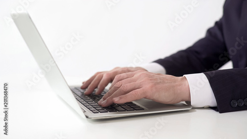 Hands of successful businessman typing on laptop, working on project report