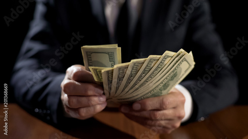 Corrupt official holding bundle of money, taking bribe for abuse of power