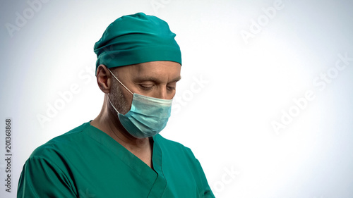 Thoughtful male surgeon put on face mask before serious operation, concentrated